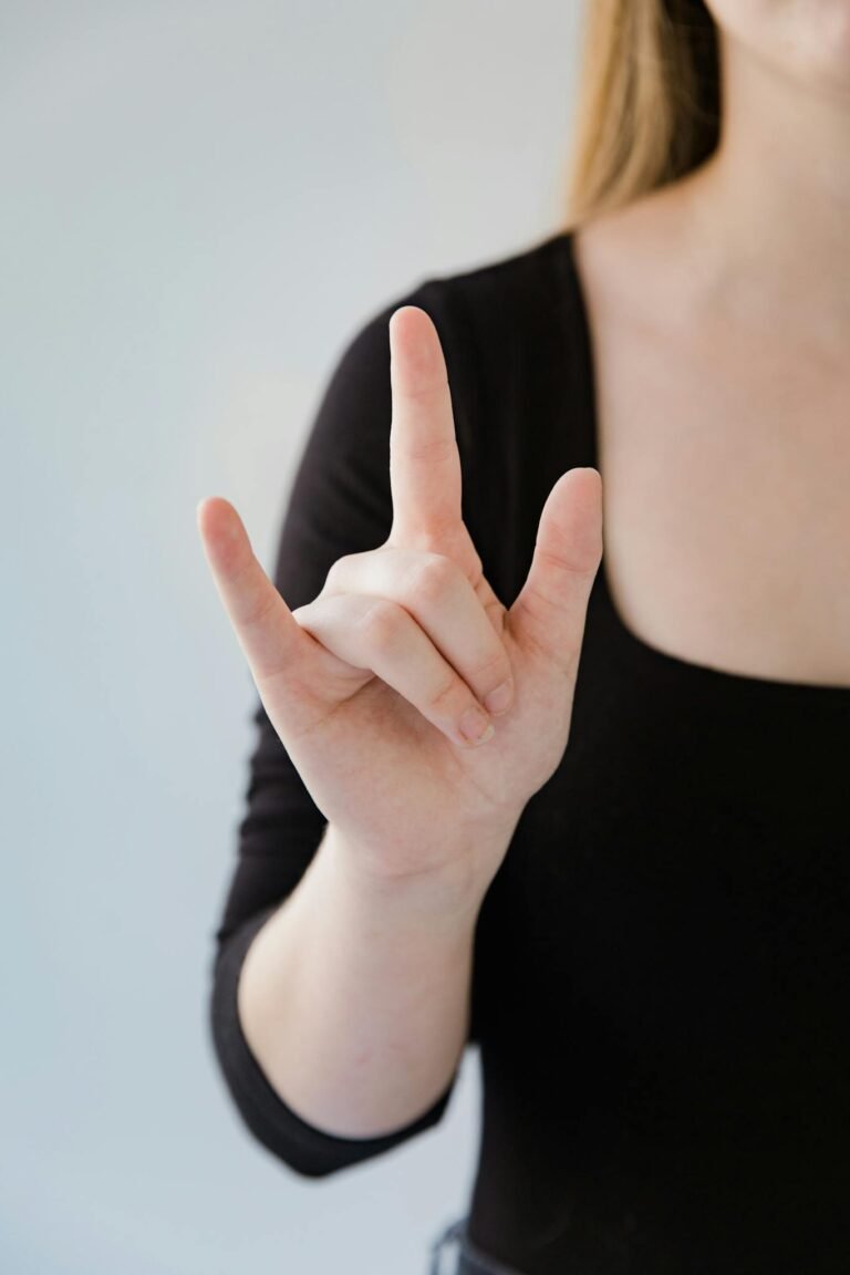 Close-up of a woman making a sign language gesture with her hand on a white background.